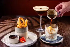 Churros with chocolate sauce and a strawberry sit beside an espresso martini as coffee is poured over vanilla ice cream in an affogato glass.
