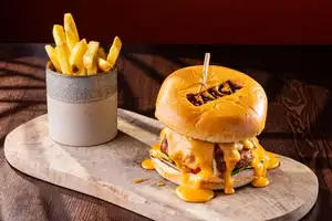 A loaded beef burger in a branded Barça brioche bun with cheese sauce, pulled meat, lettuce and tomato, served with fries.
