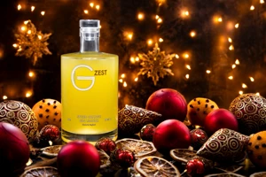 A bottle of Withers G-Zest Spiced Orange Gin Liqueur stands among dried orange slices, cinnamon sticks, star anise, pine cones and Christmas decorations.