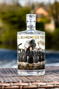 The clear bottle carries commemorative D-Day Darlings artwork and is photographed upright on the Darleys terrace during the gin launch.