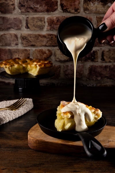 Apple pie and pouring custard, in a gastropub environment.