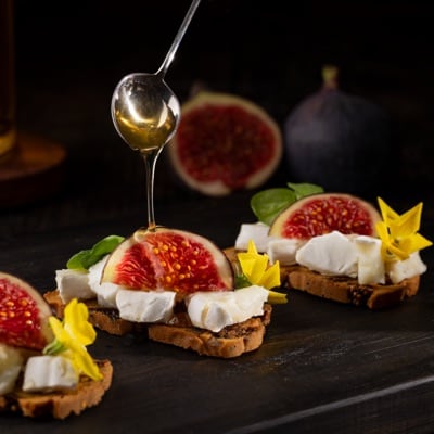 Fig and goats cheese canapés, with honey and pea shoots. Styled and photographed by JaxMore Food and Drink Photography, in their Derby studio.