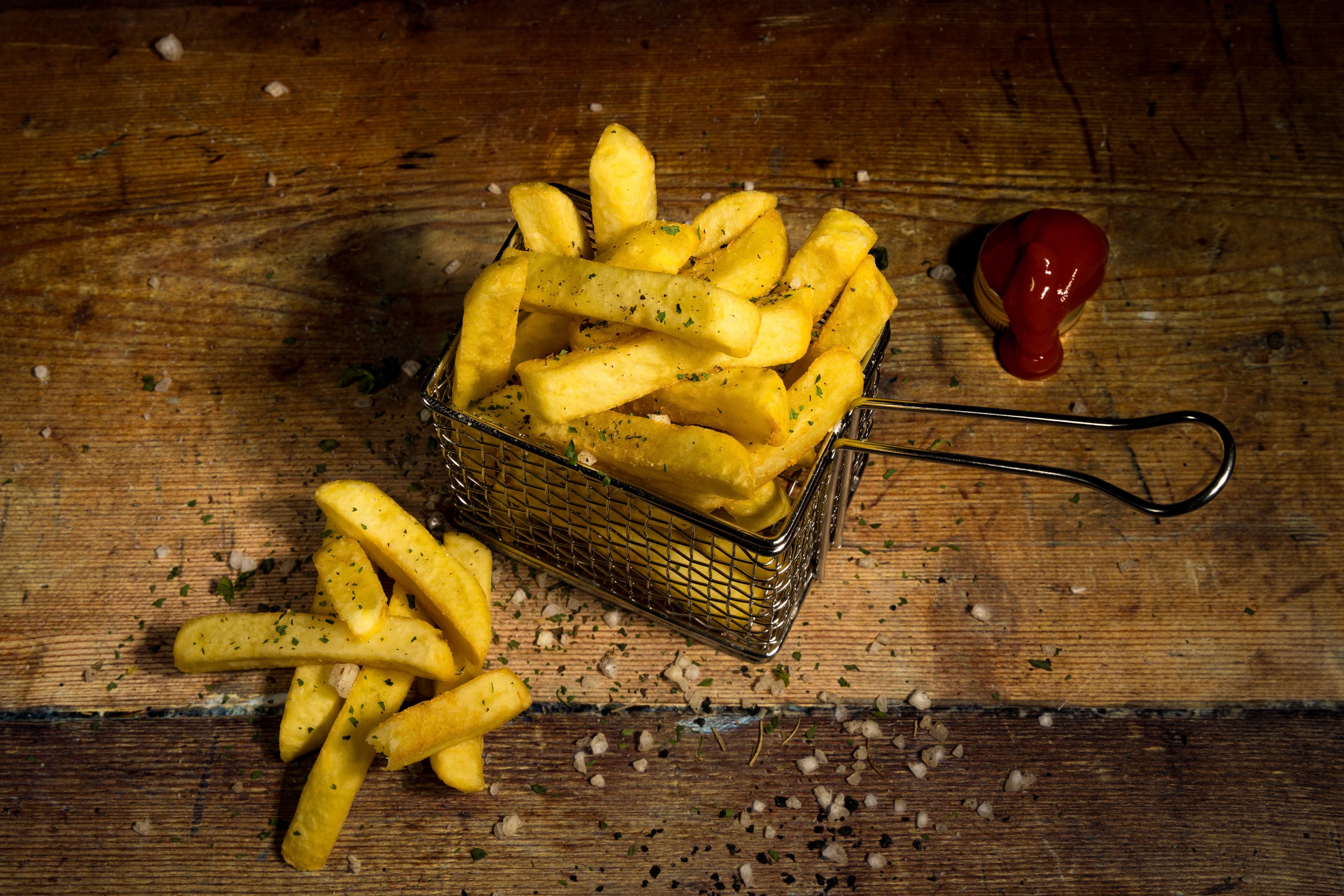 Creative photograph of a basket of chunky chips, with ketchup and rock salt.  Shot for Hopwells by Derby-based JaxMore Food and Drink Photography, on location.
