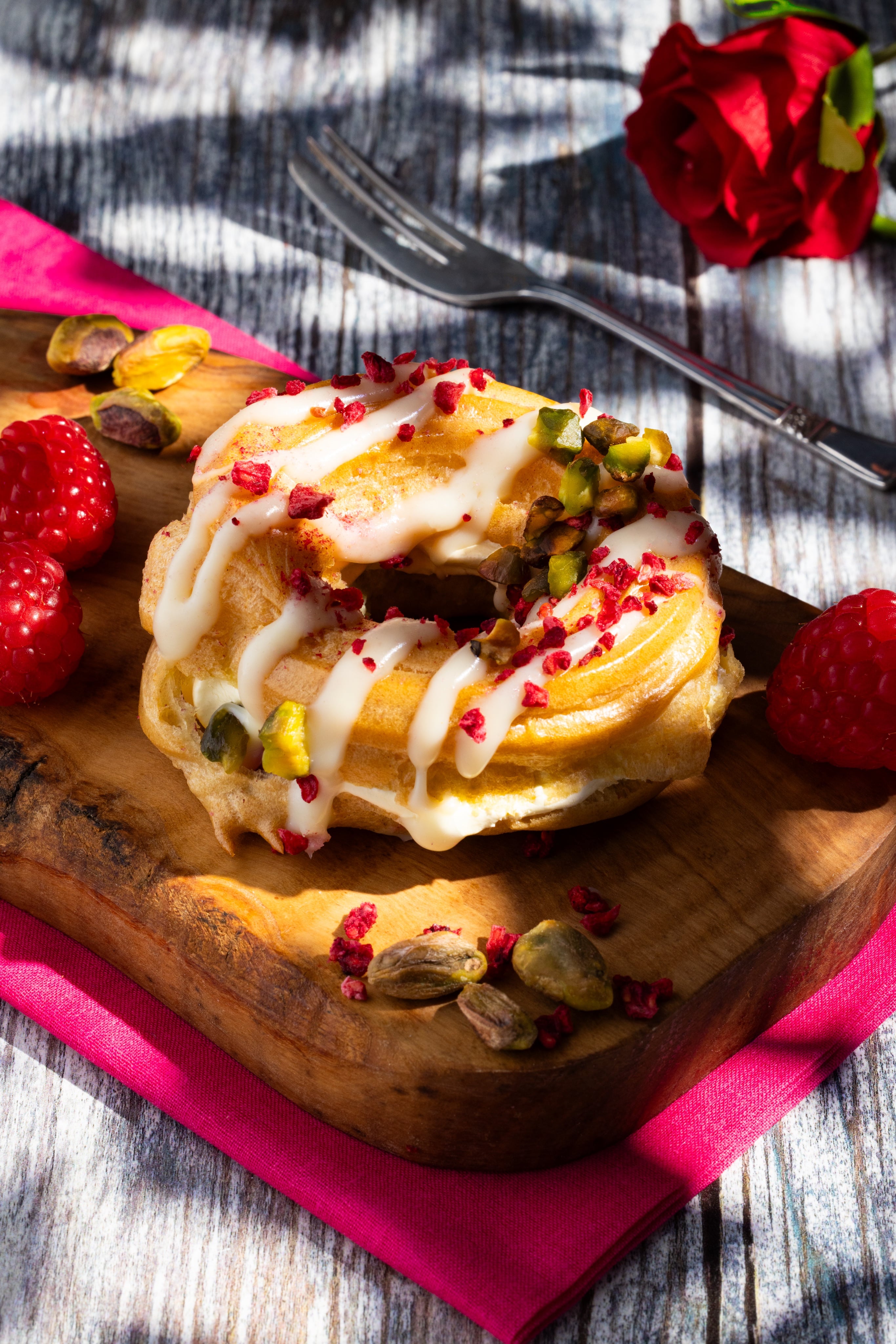 A photo of a Raspberry and Pistachio Pastry dessert, with lighting to look like a sunny day. shot by JaxMore Food and Drink Photography, in their Derby studio.