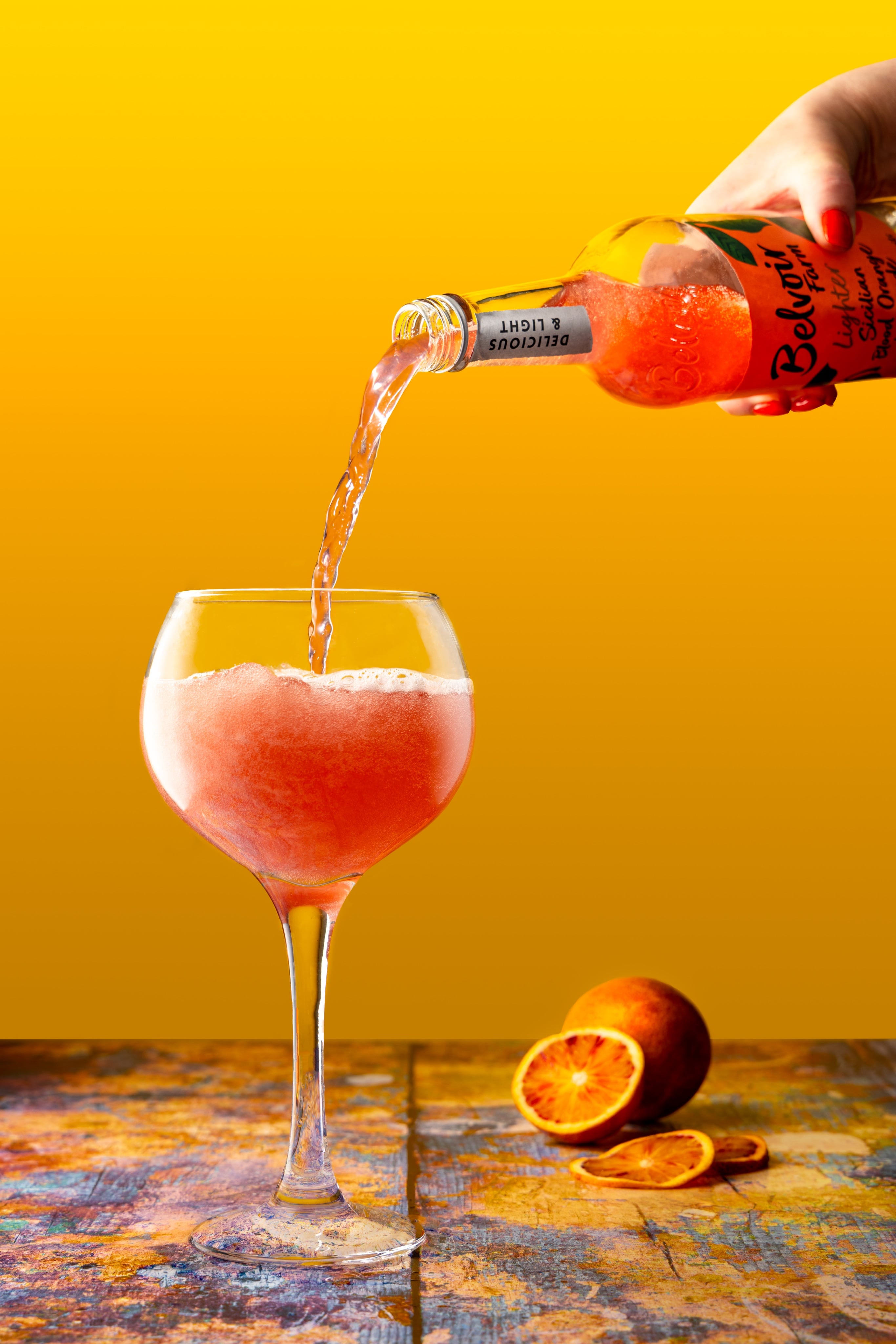 Gently sparkling, richly coloured Belvoir Farm Blood Orange Lemonade makes a vibrant image.  A creative Drinks Photograph, by JaxMore Food and Drink Photography, shot in their Derby studio.
