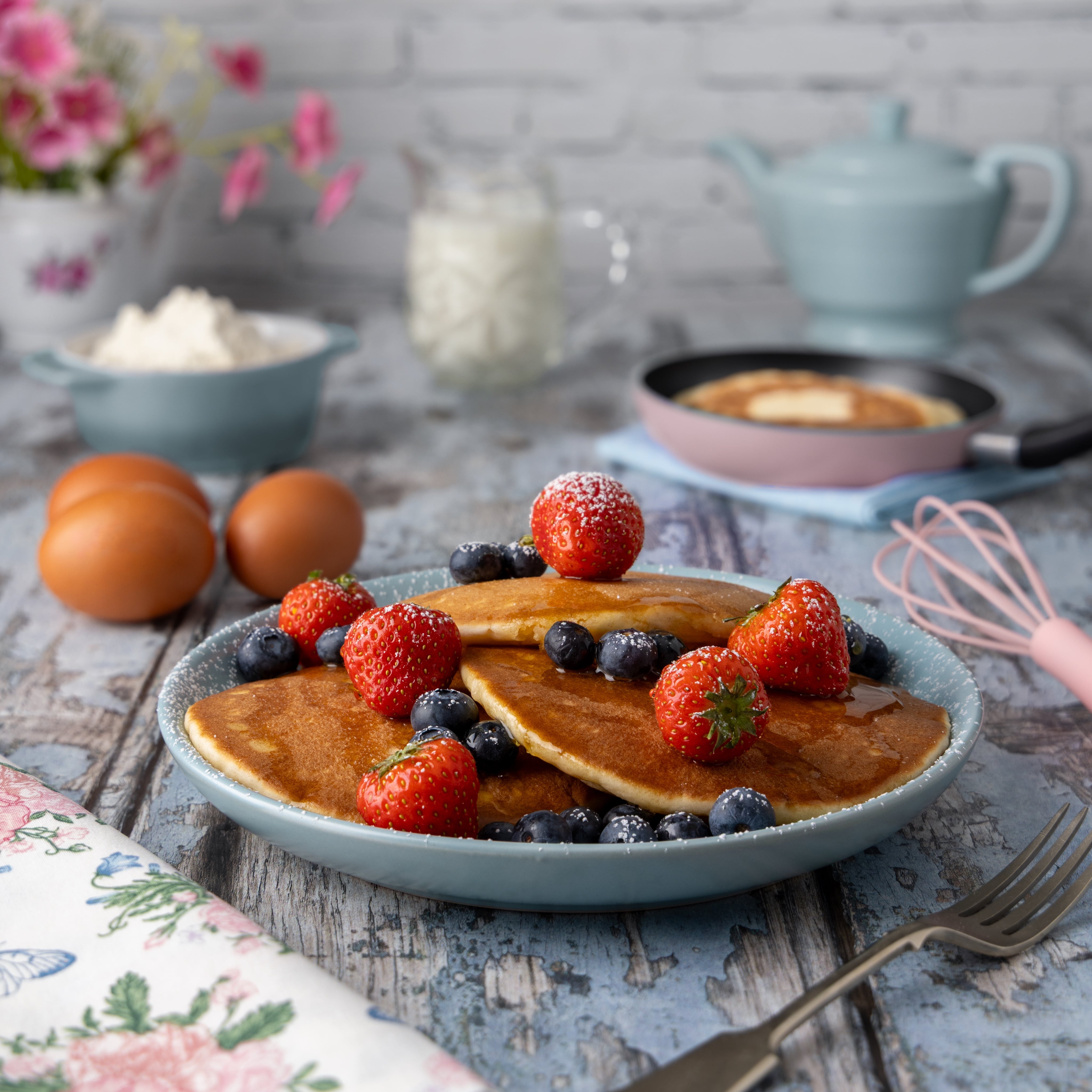 Making pancakes is always a treat! A creative food photograph, with berries, pancakes and syrup. By JaxMore Food and Drink Photography, shot in their Derby studio.