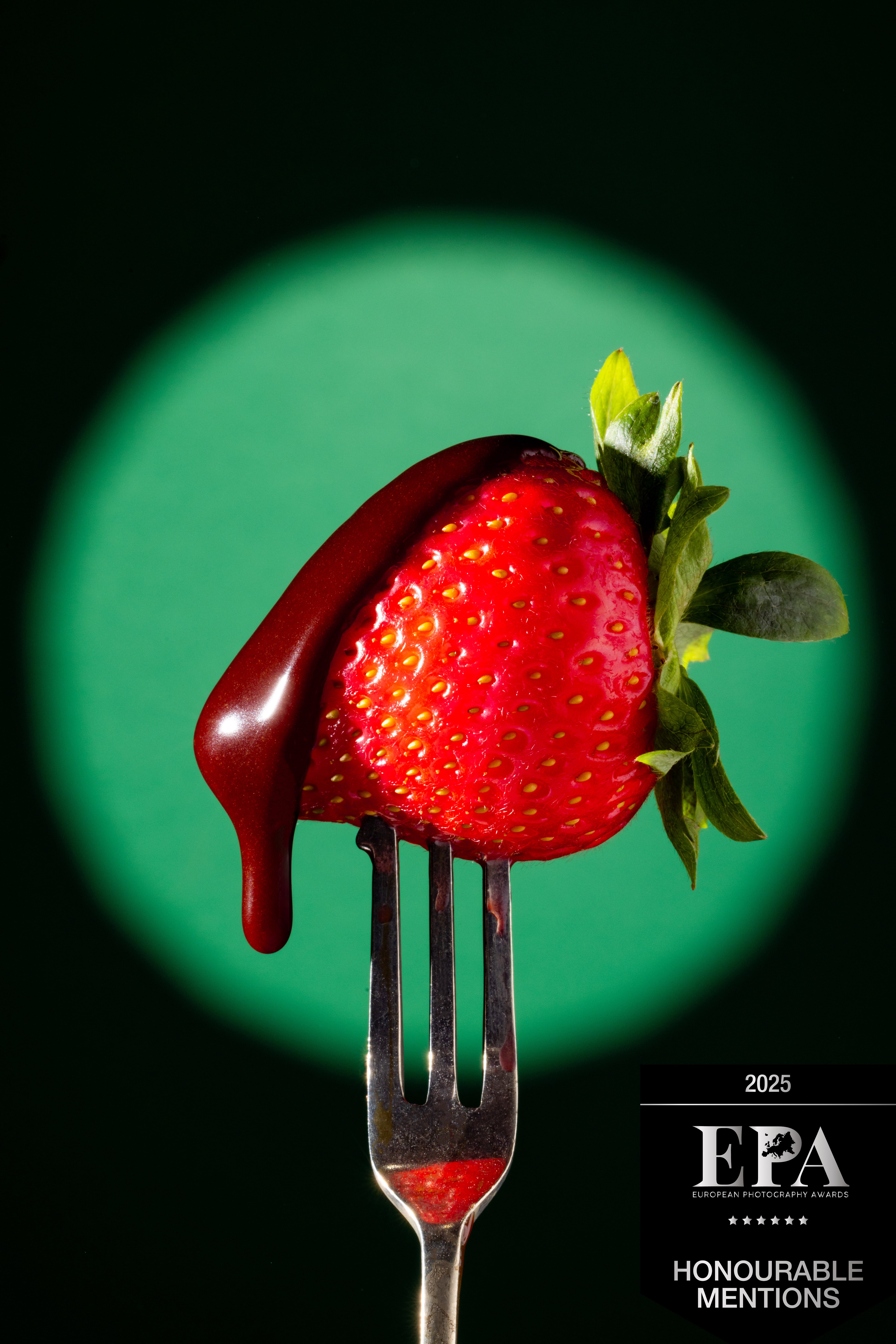 Creative Photograph of a strawberry, dripping with chocolate, balanced on a fork. Shot by JaxMore Food and Drink Photography, in their Derby studio.
