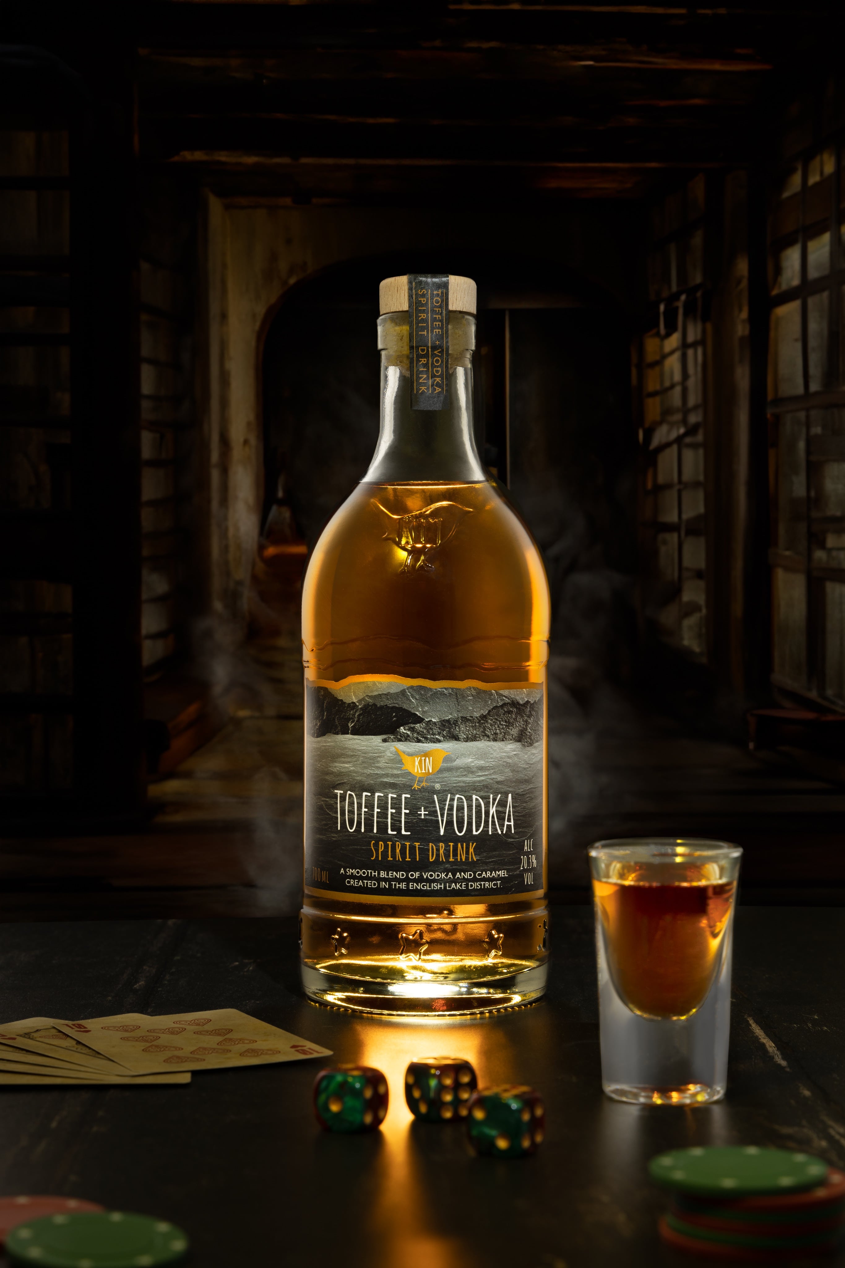 Creative photograph of bottle of Toffee Vodka with a glass, set in an atmospheric bar. Shot by JaxMore Food and Drink Photography, in their Derby studio.