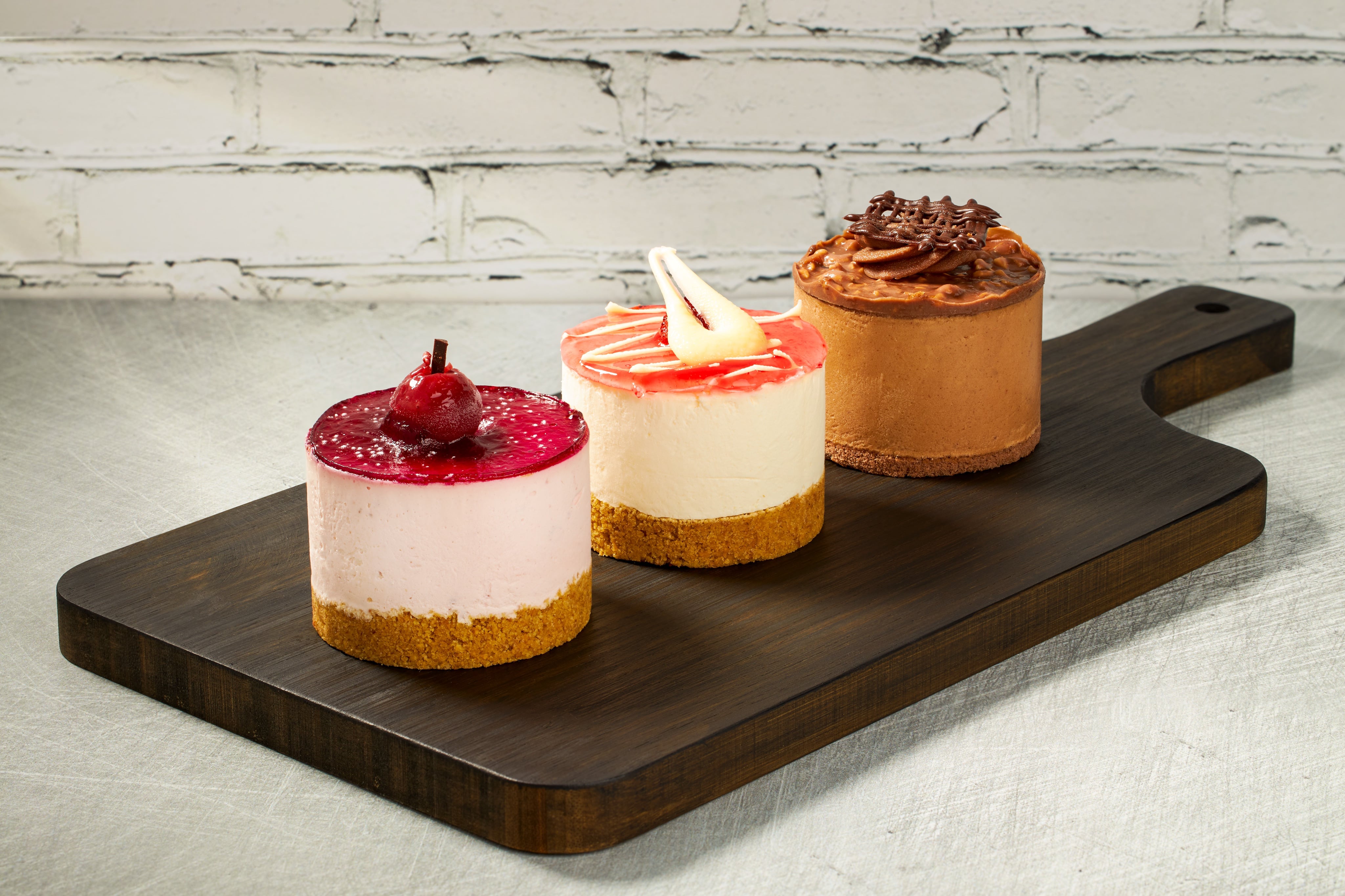Creative photograph of three delicious cheesecakes, on a wooden serving board. Shot by JaxMore Food and Drink Photography, in their Derby studio.