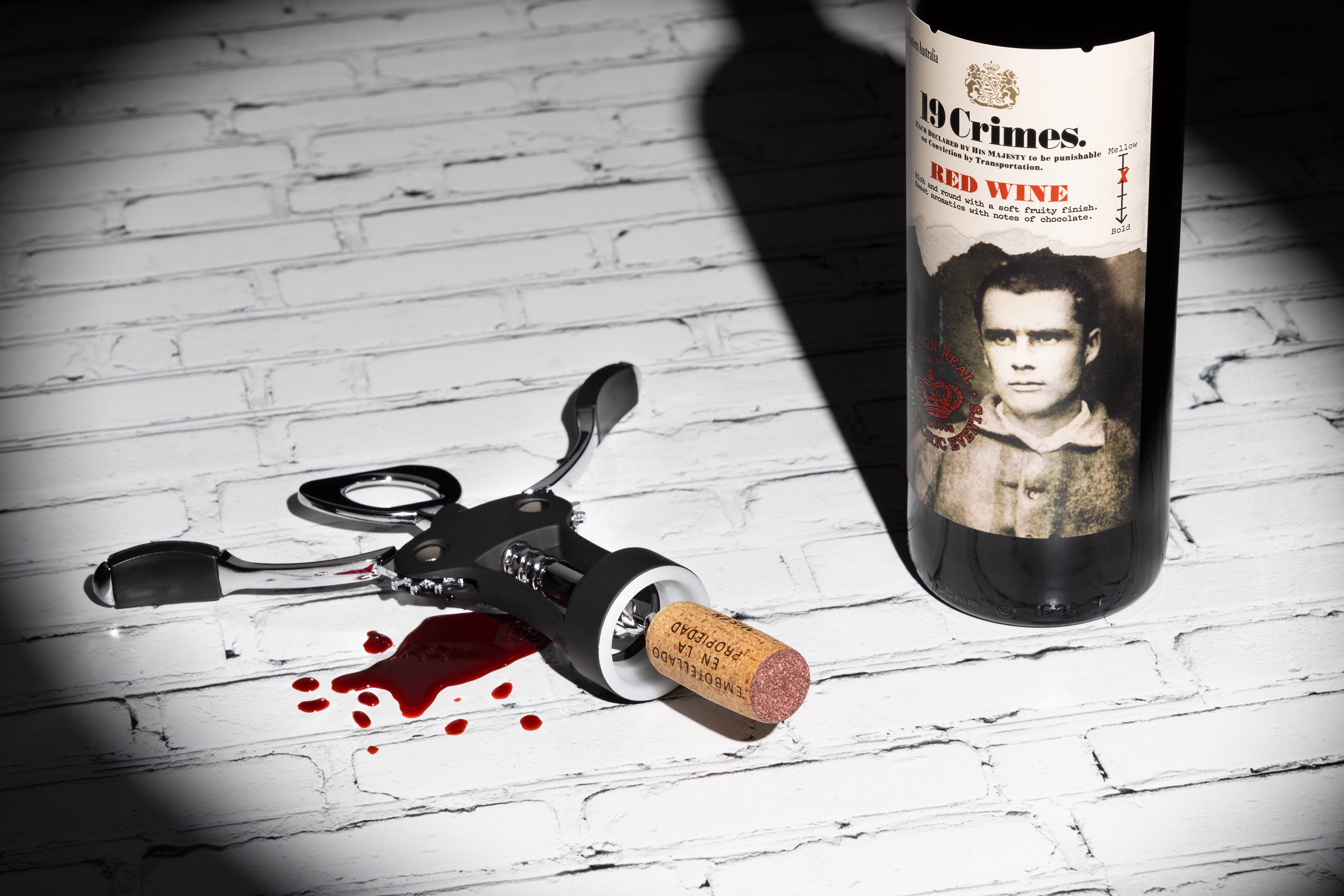 Creative photograph of a wine crime. A bottle of 19 Crimes Red Wine, conquering Old World wines. By JaxMore Food and Drink Photography, shot in their Derby studio.